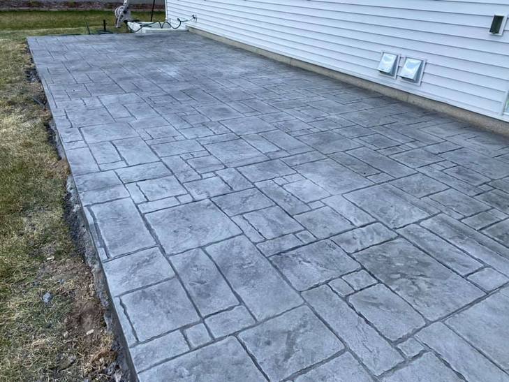 Grey stamped concrete patio poured along the side of a home